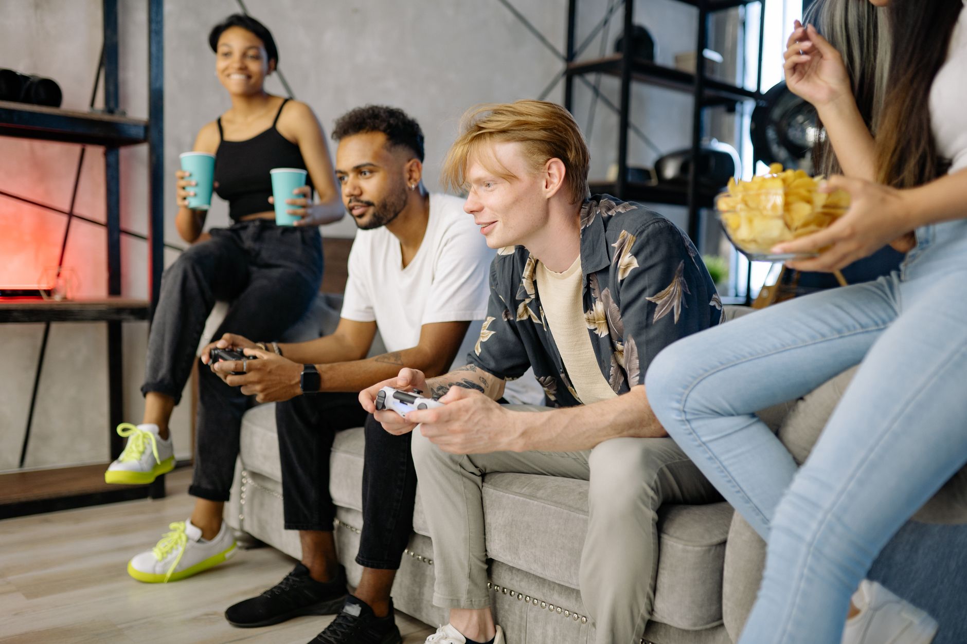 Plusieurs jeunes adultes réunis dans un salon, manettes de jeu vidéo en main devant un canapé.